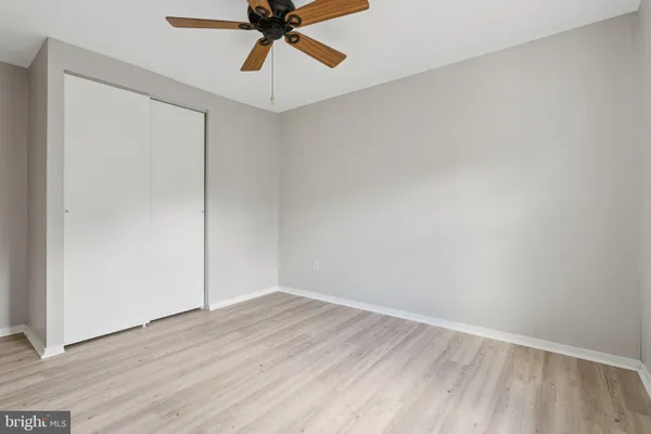 an empty room with wooden floor fan and windows