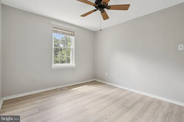 an empty room with a window and a fan
