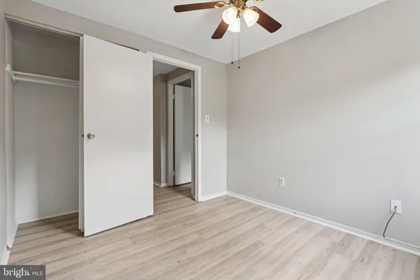 an empty room with wooden floor and chandelier fan