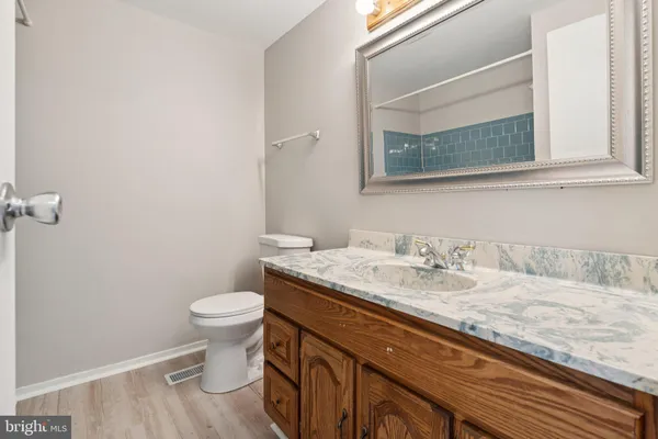 a bathroom with a granite countertop sink and a toilet