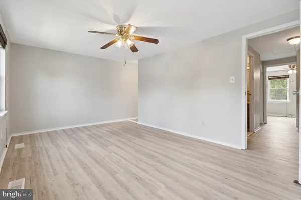 an empty room with wooden floor chandelier fan and closet area
