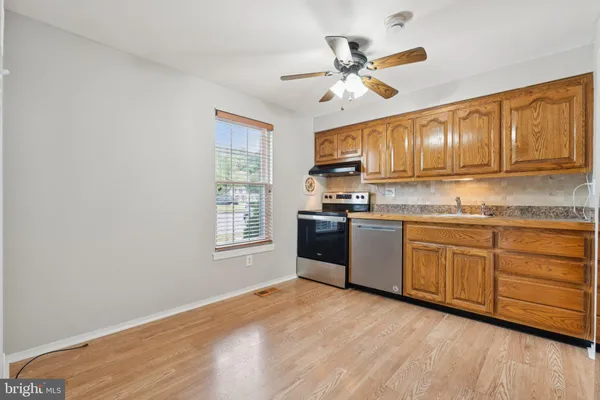 a kitchen with granite countertop wooden cabinets a sink a window and appliances
