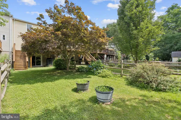 a backyard of a house with table and chairs potted plants and large tree