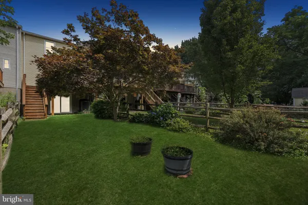 a view of a backyard with couches plants and large trees