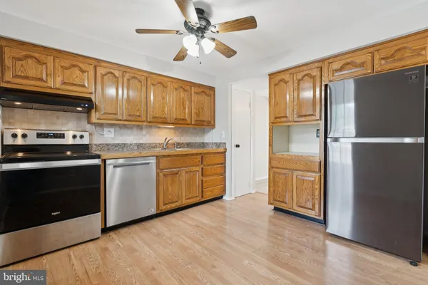 a kitchen with stainless steel appliances granite countertop a refrigerator a stove a sink and dishwasher with wooden floor