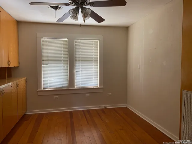 an empty room with wooden floor fan and windows