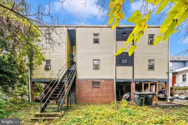 a view of backyard of house with outdoor seating and covered with trees