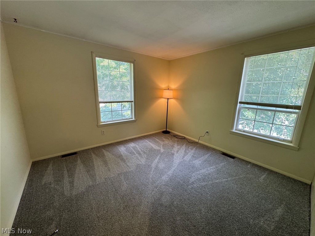 7294 Fox Mill Road, Unit 19D Mentor, OH 44060 - Photo 23 of 27 Spacious room featuring neutral-toned walls, gray patterned carpeting, and two large windows with blinds