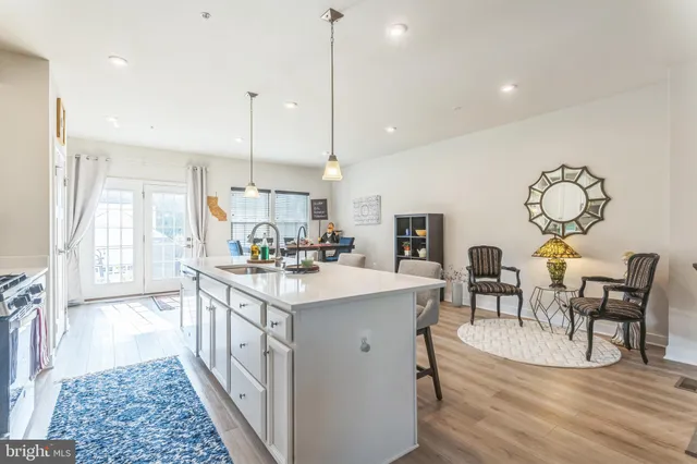 a open kitchen with stainless steel appliances granite countertop a stove top oven a sink dishwasher a dining table and chairs with wooden floor