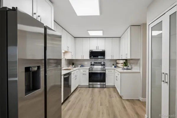 a kitchen with cabinets stainless steel appliances and wooden floor