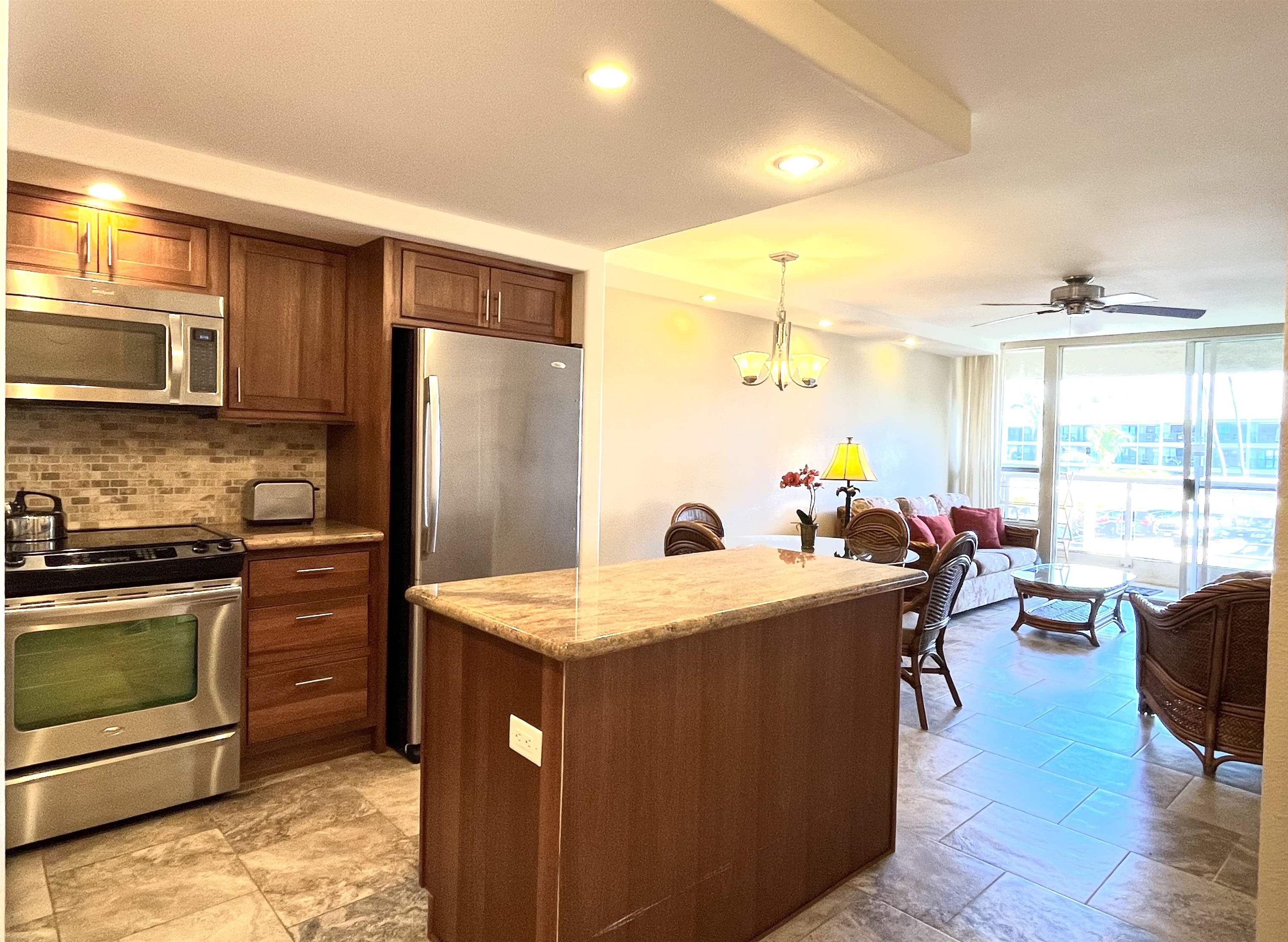 2575 South Kihei Road, Unit H414 Kihei, HI 96753 - Photo 6 of 30 a kitchen with a stove a refrigerator and a dining table with wooden floor