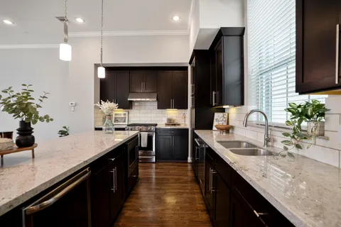 a kitchen with kitchen island granite countertop a sink stainless steel appliances and cabinets
