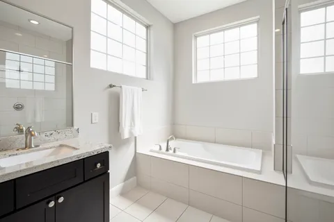 a spacious bathroom with a tub sink and mirror