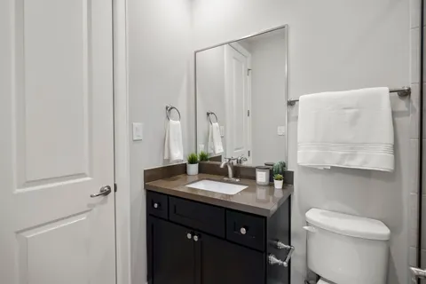 a bathroom with a granite countertop sink toilet and mirror