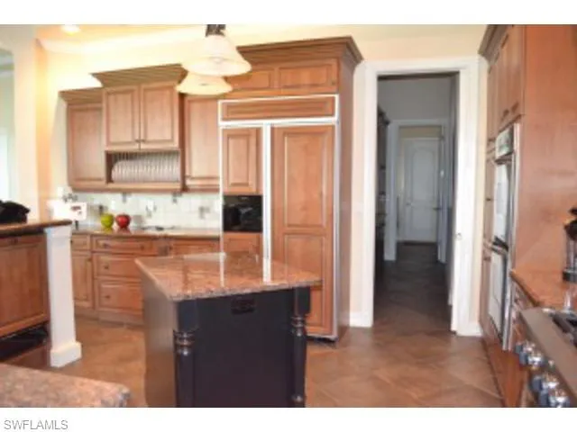 a kitchen with kitchen island granite countertop a sink cabinets and stainless steel appliances