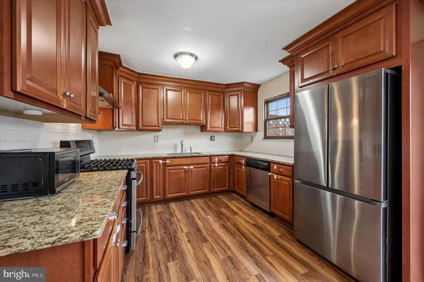a kitchen with granite countertop stainless steel appliances a refrigerator stove top oven and sink