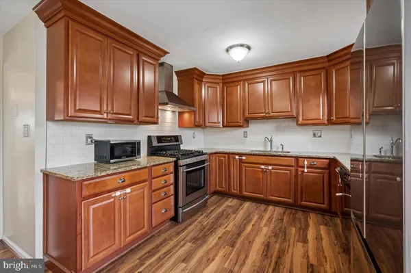 a kitchen with stainless steel appliances granite countertop wooden cabinets a stove top oven a sink and dishwasher