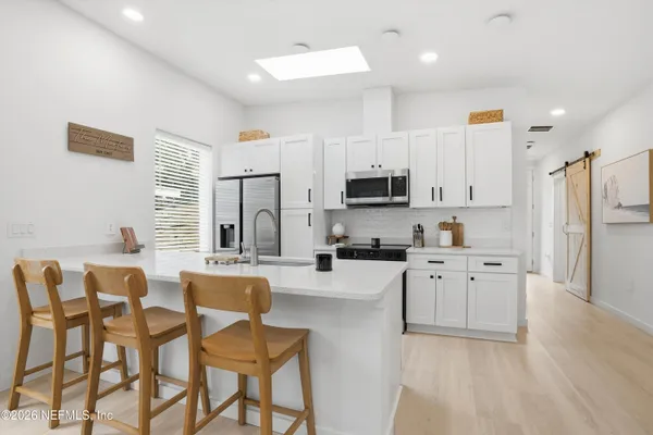 a kitchen with stainless steel appliances white cabinets and wooden floor