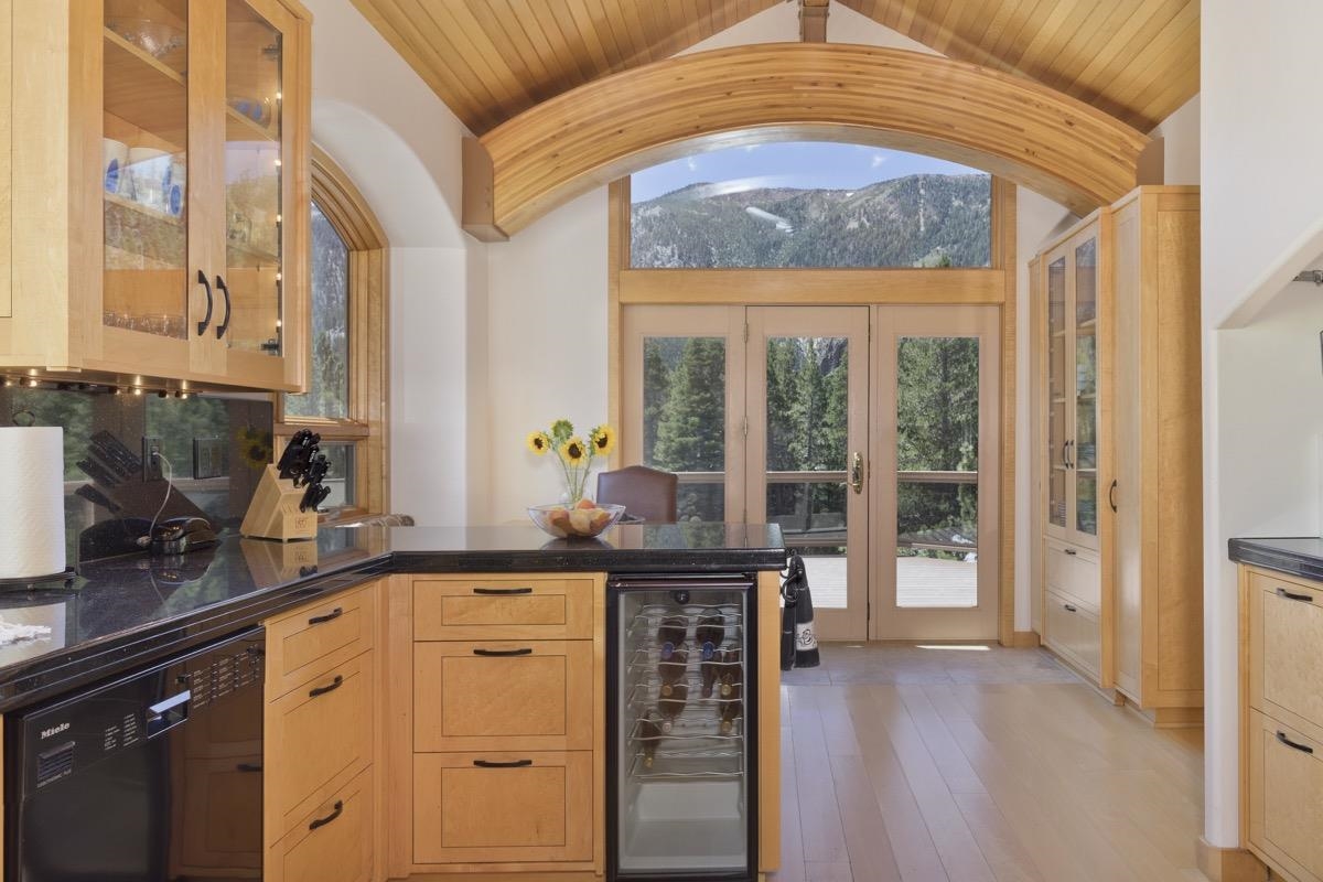 92 Garnet Street Mammoth Lakes, CA 93546 - Photo 11 of 50 Kitchen featuring dishwasher, beverage cooler, lofted ceiling, dark countertops, and glass insert cabinets