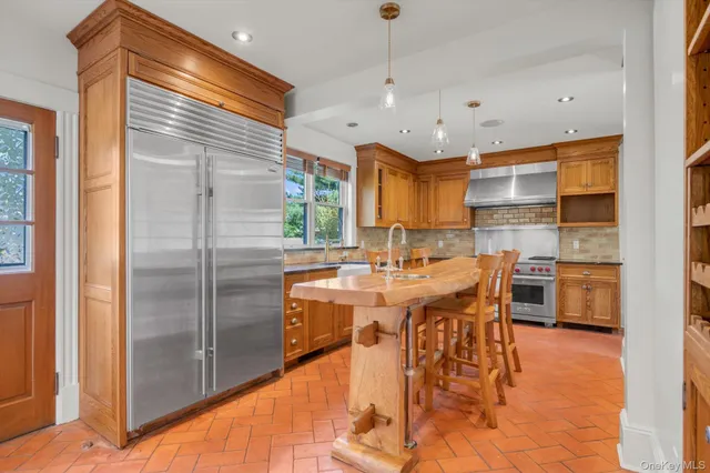 a kitchen with stainless steel appliances kitchen island granite countertop a table chairs and a refrigerator