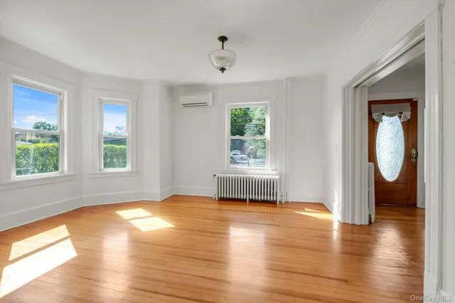 a view of an empty room with a window and wooden floor