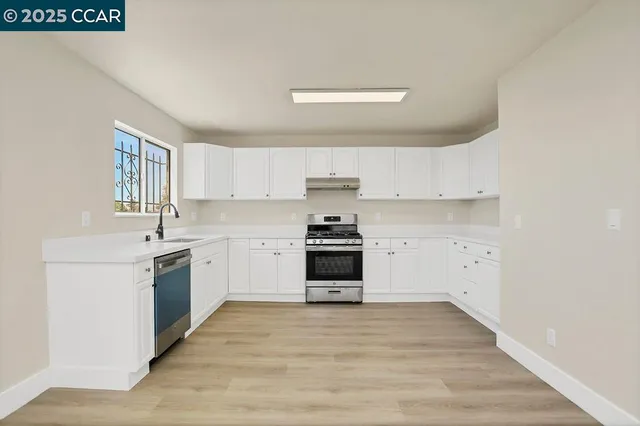 a kitchen with granite countertop white cabinets and stainless steel appliances