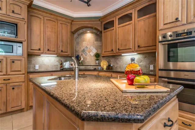 a kitchen with granite countertop a sink a stove and lots of wooden cabinets