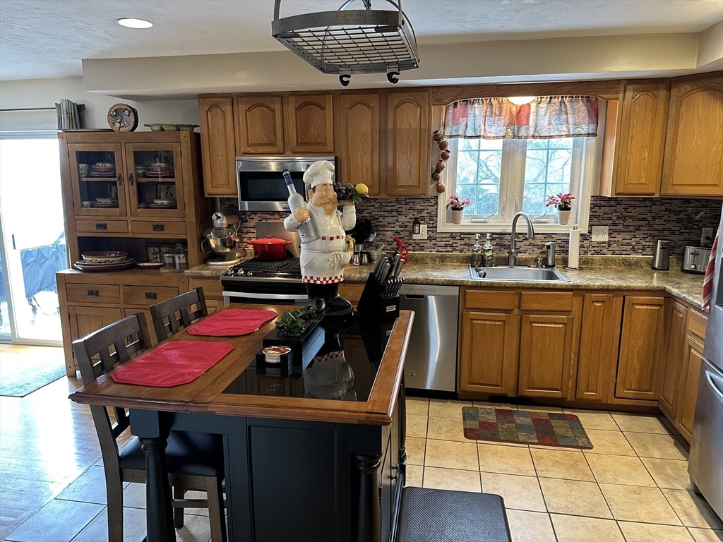 28 Ely Street Randolph, MA 02368 - Photo 4 of 28 a kitchen with a refrigerator a stove top oven a sink dishwasher and dining table with wooden floor