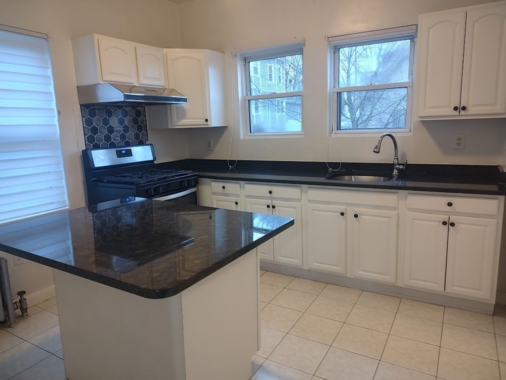 378 Ferry Street Everett, MA 02149 - Photo 3 of 26 a kitchen with granite countertop a sink a stove and cabinets