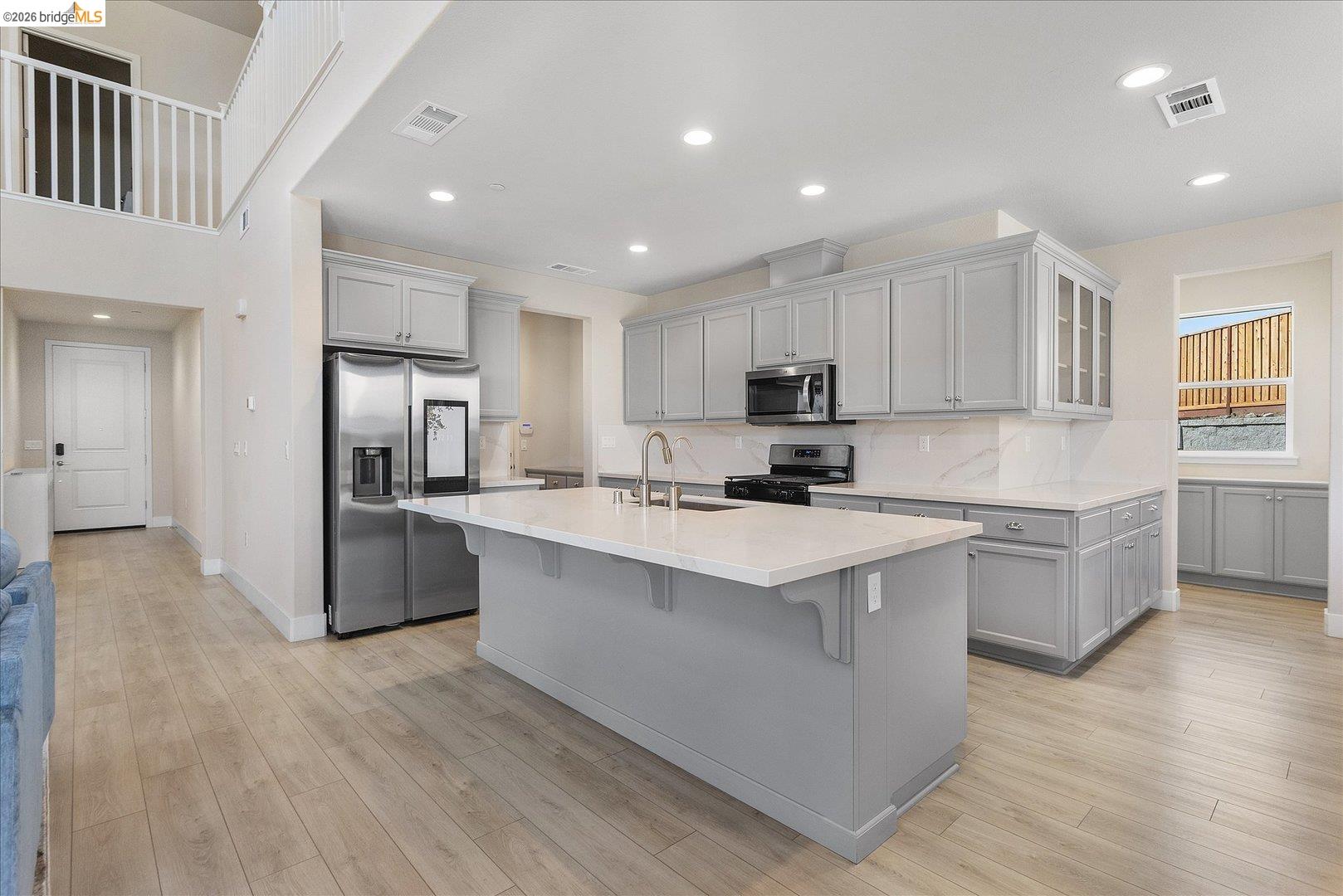 5601 Ridgepoint Way Antioch, CA 94531 - Photo 11 of 59 Open-concept kitchen featuring an oversized island with countertop seating, light gray cabinetry, stainless steel appliances, and wood-finish flooring