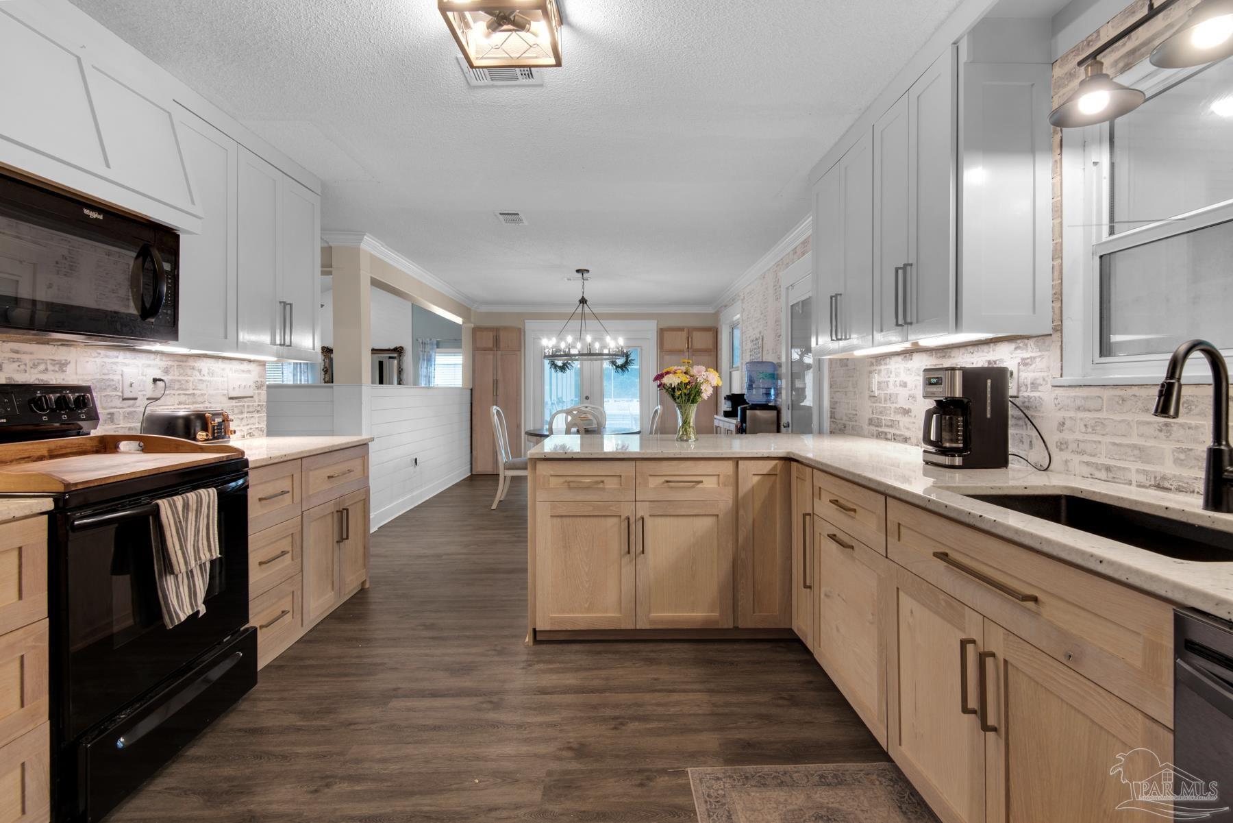 a kitchen with stainless steel appliances granite countertop a stove top oven a sink dishwasher and a microwave oven with white cabinets