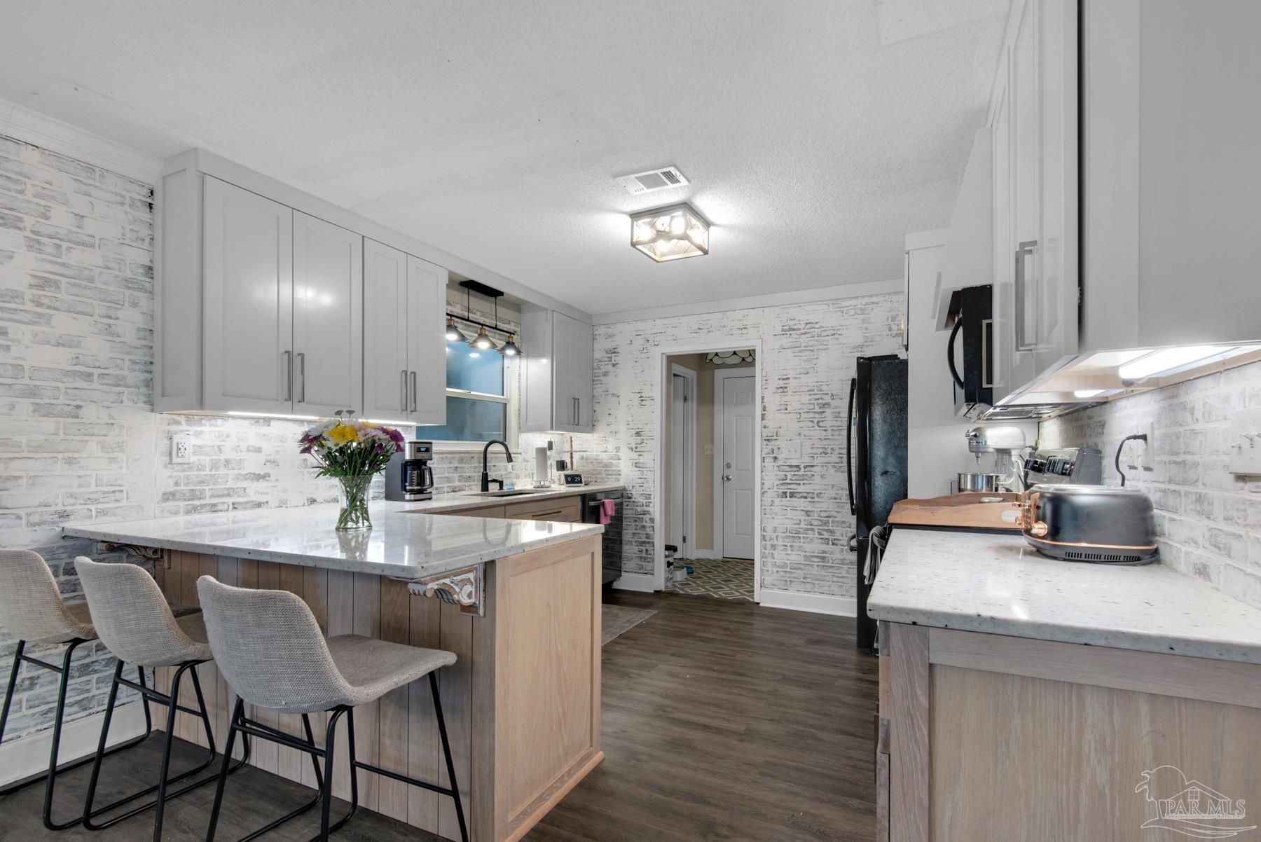 4316 Highland Boulevard Pace, FL 32571 - Photo 14 of 43 a kitchen with stainless steel appliances kitchen island granite countertop a table chairs and a refrigerator