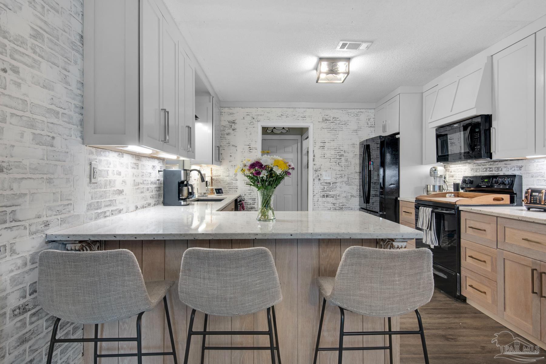 4316 Highland Boulevard Pace, FL 32571 - Photo 15 of 43 a kitchen with stainless steel appliances granite countertop a sink a stove a refrigerator cabinets and chairs