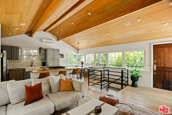 a kitchen with stainless steel appliances kitchen island granite countertop a dining table chairs and a refrigerator