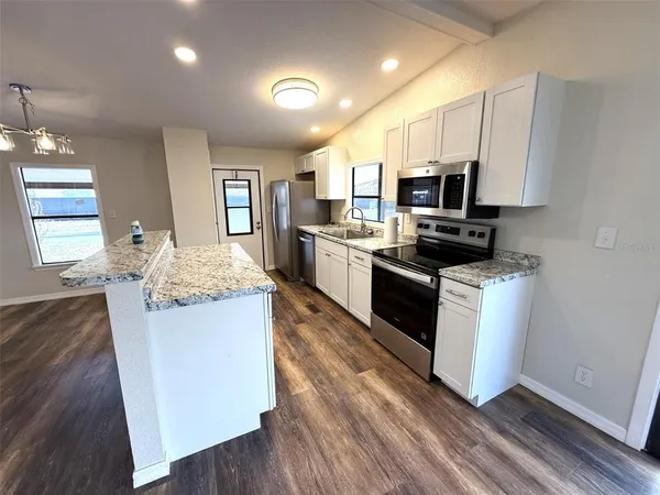 a large kitchen with stainless steel appliances granite countertop a stove top oven a sink dishwasher and a refrigerator