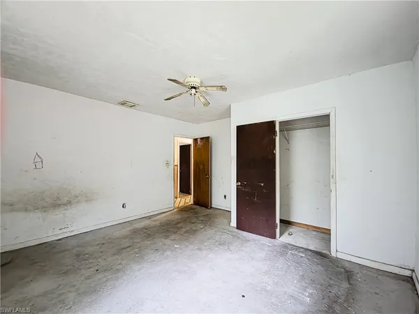 an empty room with closet and a ceiling fan