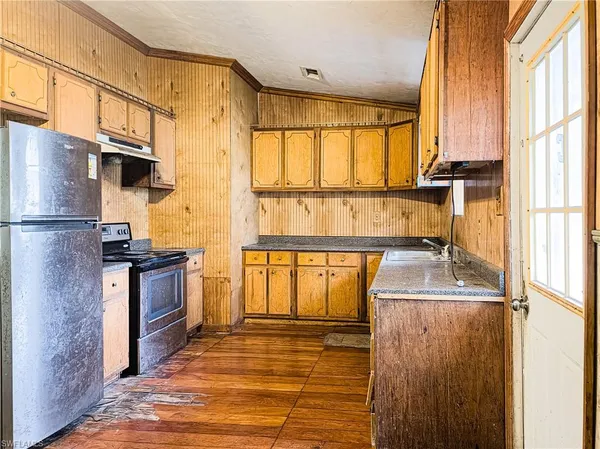 a kitchen with stainless steel appliances granite countertop a refrigerator a stove and a sink with wooden floor
