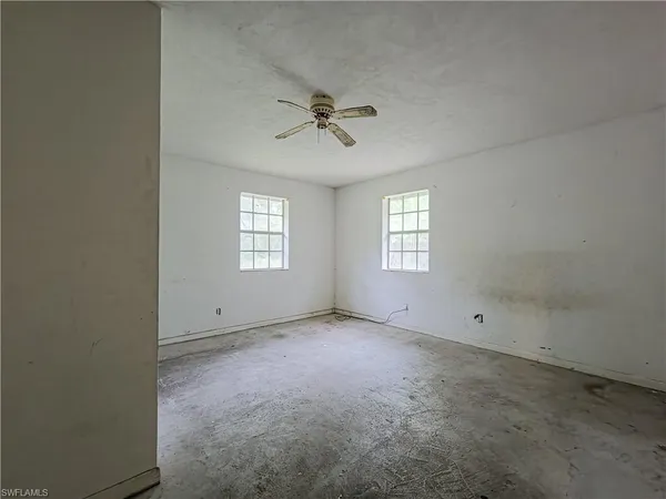 an empty room with windows and ceiling fan view