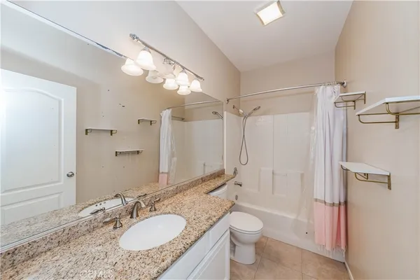 a bathroom with a granite countertop sink toilet a shower and a mirror
