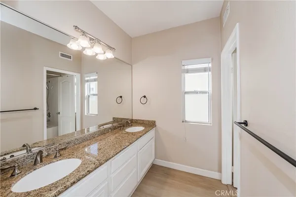 a bathroom with a granite countertop sink a light fixture and a mirror