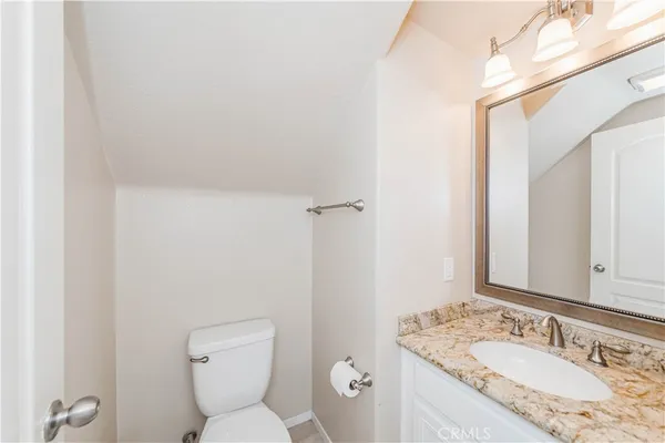 a bathroom with a granite countertop toilet a sink and a mirror