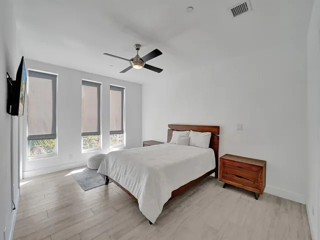 a bedroom with a bed a ceiling fan and a large window