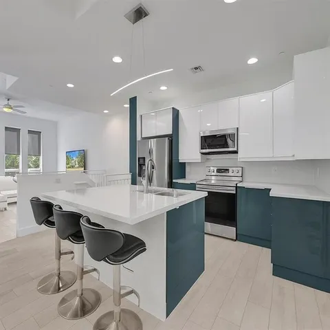 a kitchen with stainless steel appliances kitchen island granite countertop a stove a sink a microwave a dining table and chairs