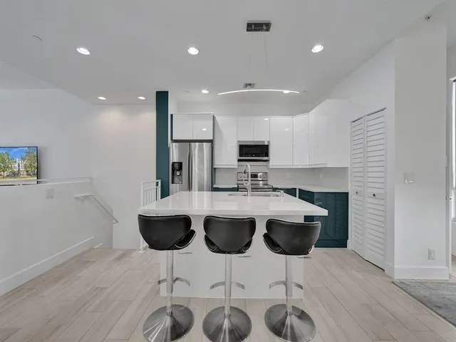 a kitchen with stainless steel appliances kitchen island granite countertop a wooden cabinets and a chairs