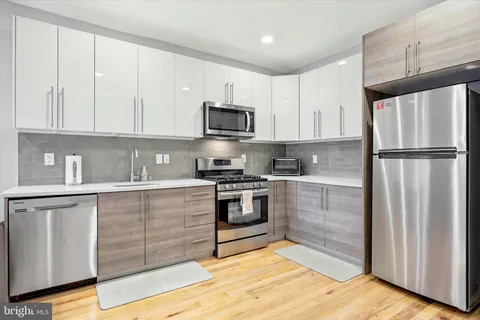 a kitchen with granite countertop a refrigerator stove and white cabinets