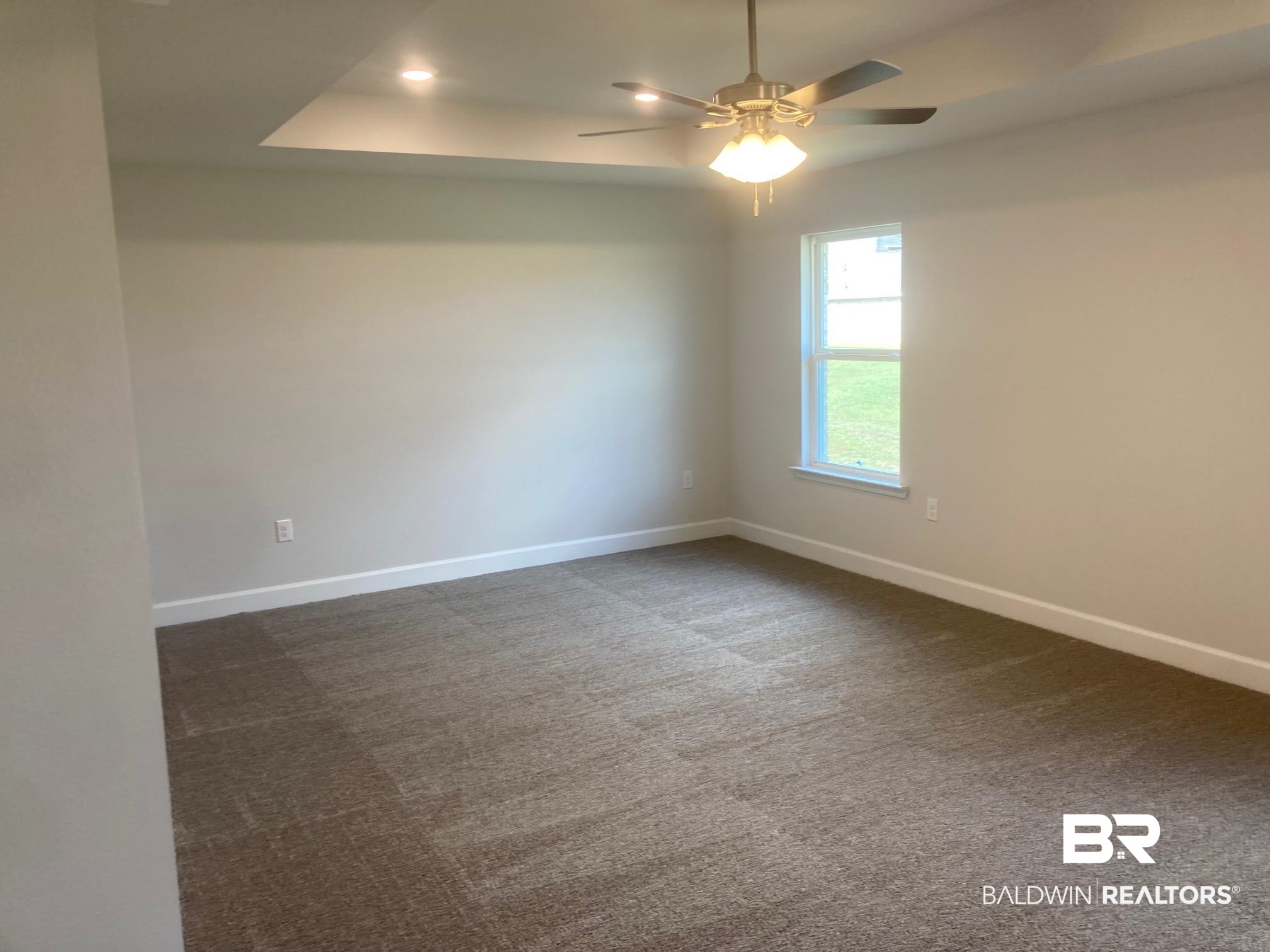 629 Revere Street Foley, AL 36535 - Photo 17 of 30 Spare room featuring a tray ceiling, ceiling fan, and dark carpet