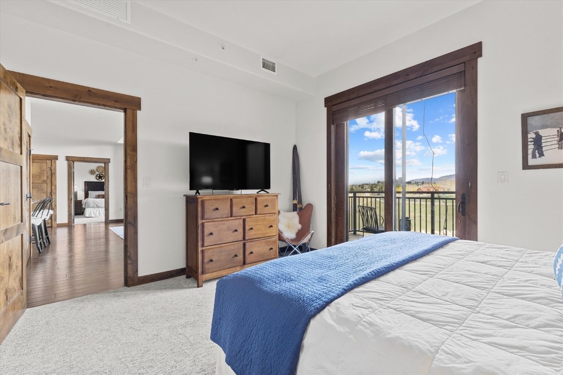 1175 Bangtail Way, Unit 5118 Steamboat Springs, CO 80487 - Photo 22 of 46 a bedroom with a large bed and a flat tv screen on dresser
