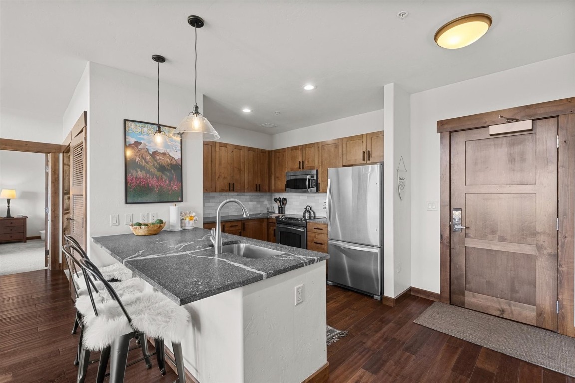 1175 Bangtail Way, Unit 5118 Steamboat Springs, CO 80487 - Photo 9 of 46 a kitchen with stainless steel appliances granite countertop a sink refrigerator and microwave