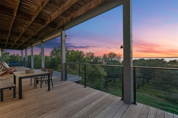 a view of a roof deck with table and chairs a barbeque with wooden floor and fence