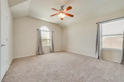 an empty room with chandelier fan and windows